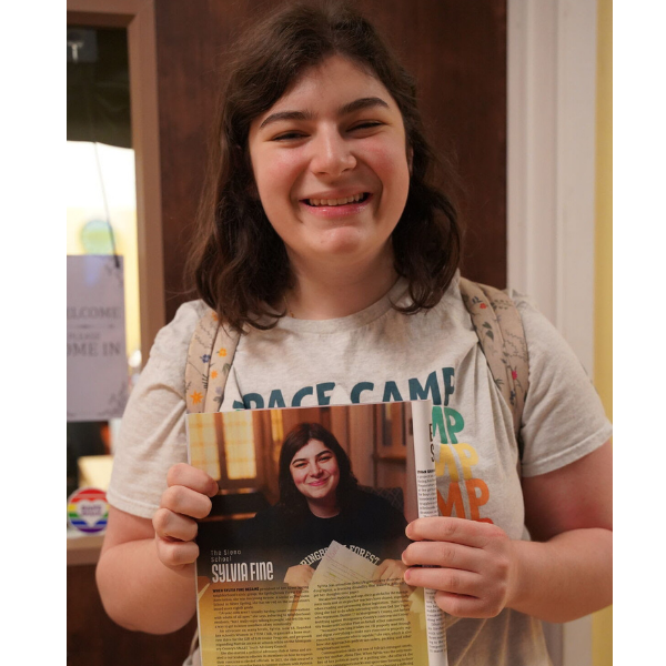 A Siena high school student proudly smiles at the camera while holding a magazine profile she's featured in.