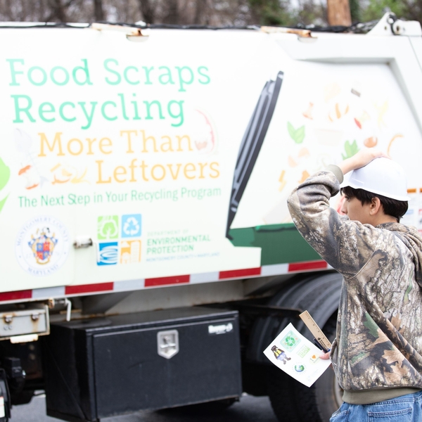 A boy wearing a construction hard had looks interestedly at a food recycling truck on Truck Day at The Siena School.