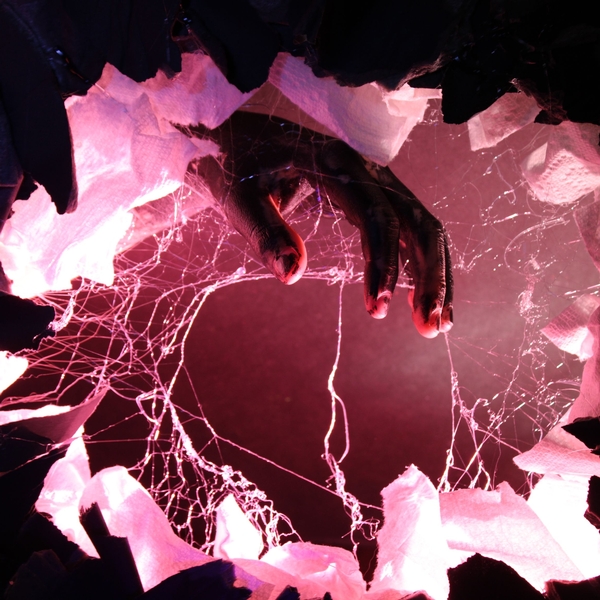 A photograph of a hand that seems to reach out from inside the image, which has a pinkish glow.