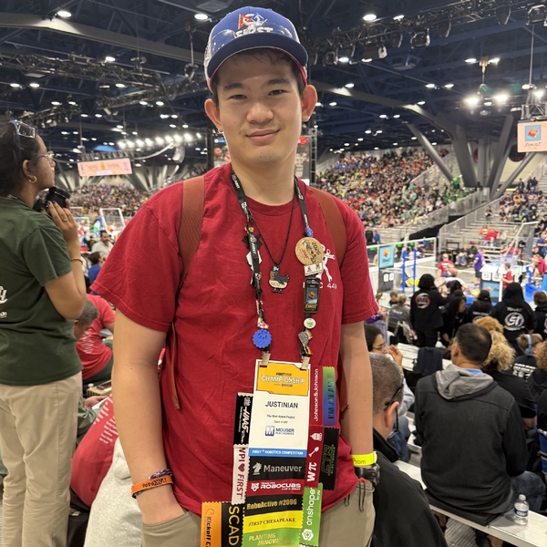 A high school student from The Siena School wearing badges from a robotics competition looks proud.