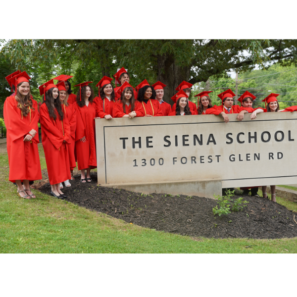 A group of high school graduates in red caps and gowns pose proudly near The Siena School's sign.