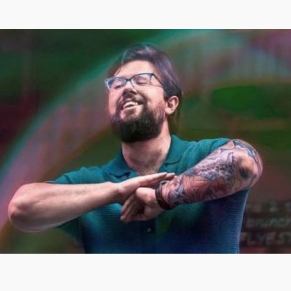 A man in a green shirt performs spoken word poetry on stage. He is engaged and energetic.