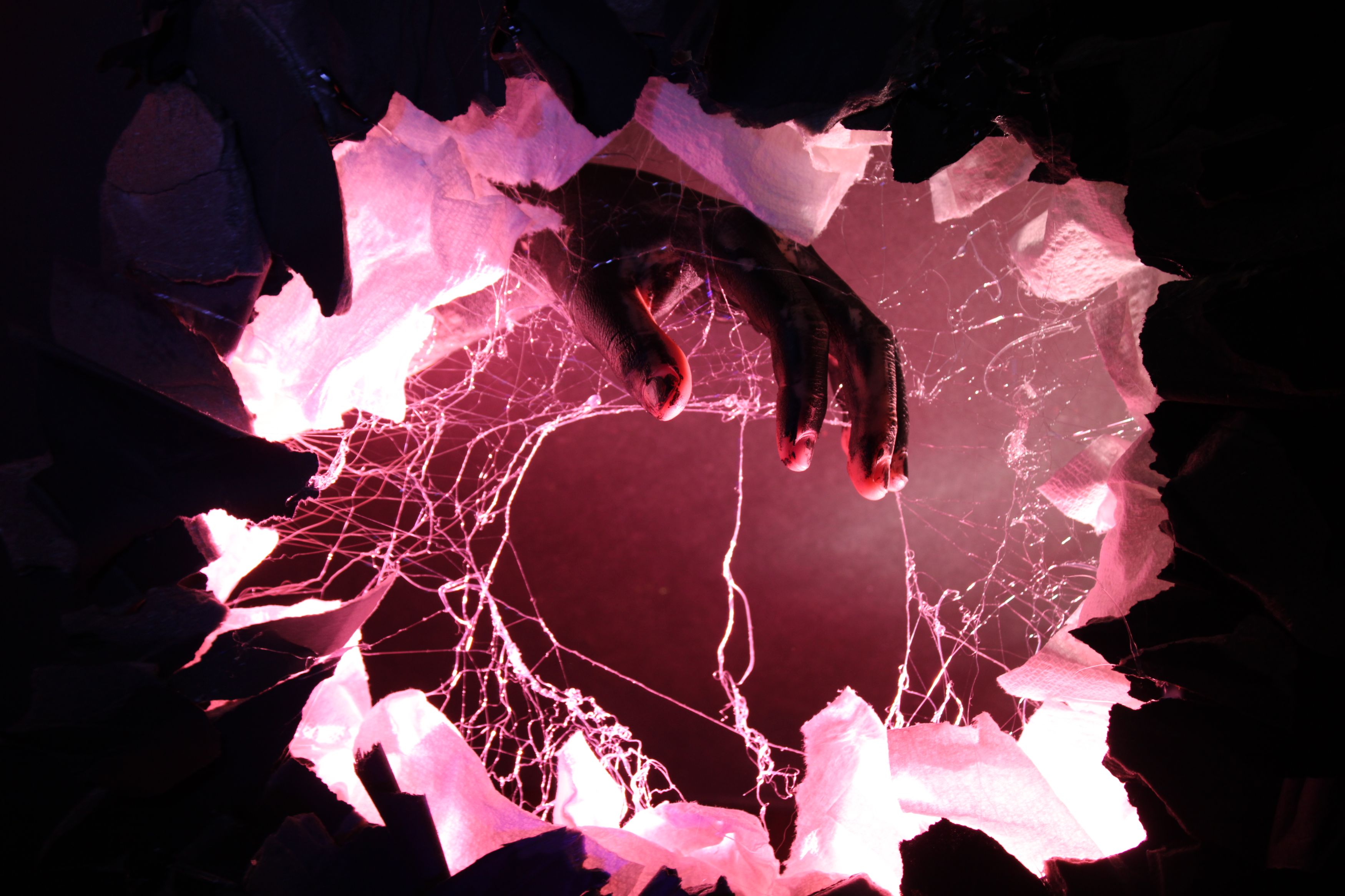 A photograph of a hand that appears to come off the page through a hole.
