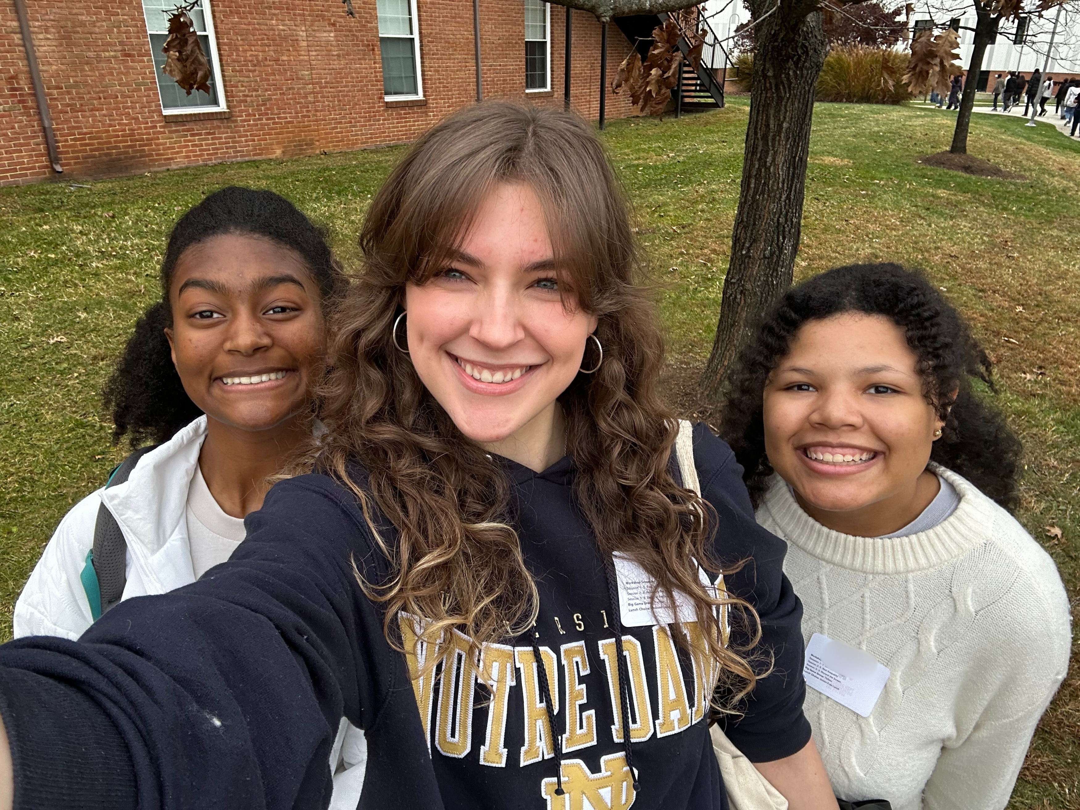 Three high school girls smile at the camera during a student leadership event. They are all smiles. 