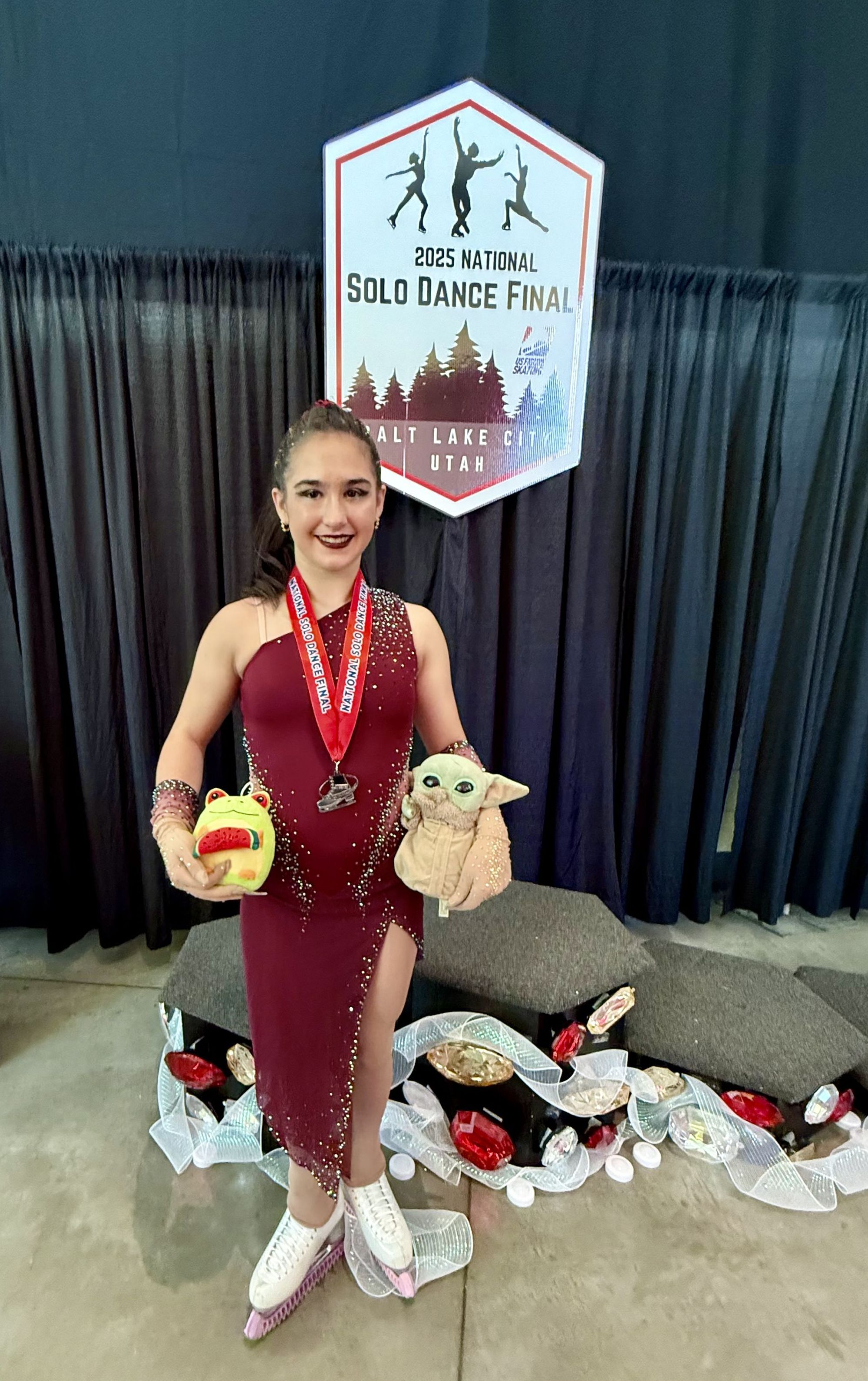 A girl in a dark costume dress wears a silver medal that she won at a national competition. 