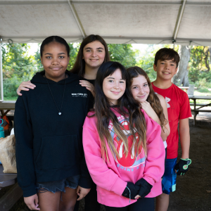 A group of middle school students smile at the camera while on a field trip.
